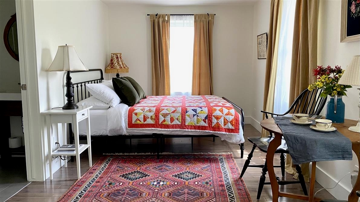 Chambre de la Cecil House avec lit en fer forgé, courtepointe colorée et mobilier rustique-chic